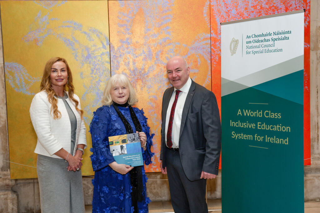 John Kearney and members of staff standing in front of a banner for the NCSE, holding a publication
