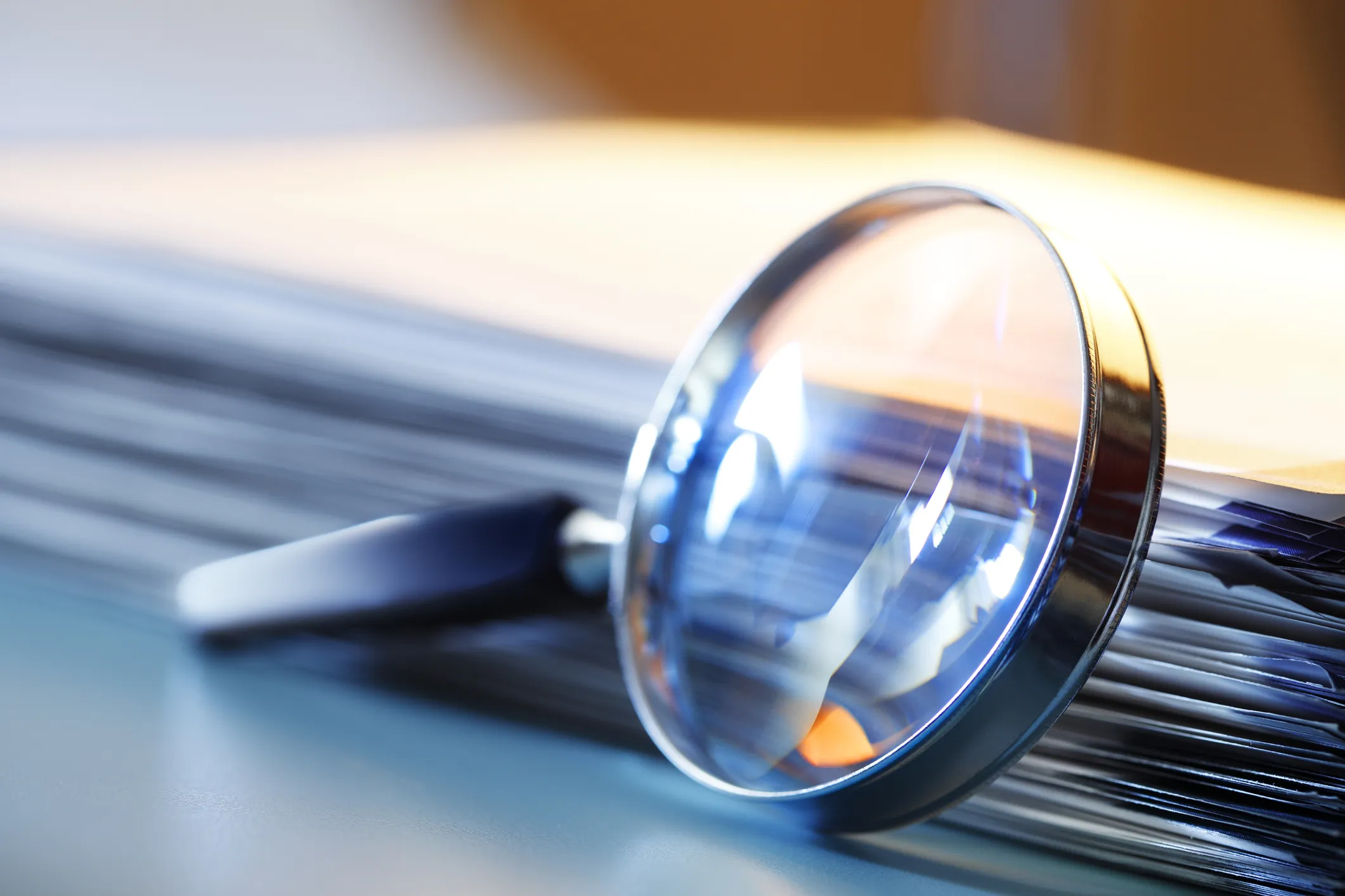 Magnifying glass resting on a stack of documents