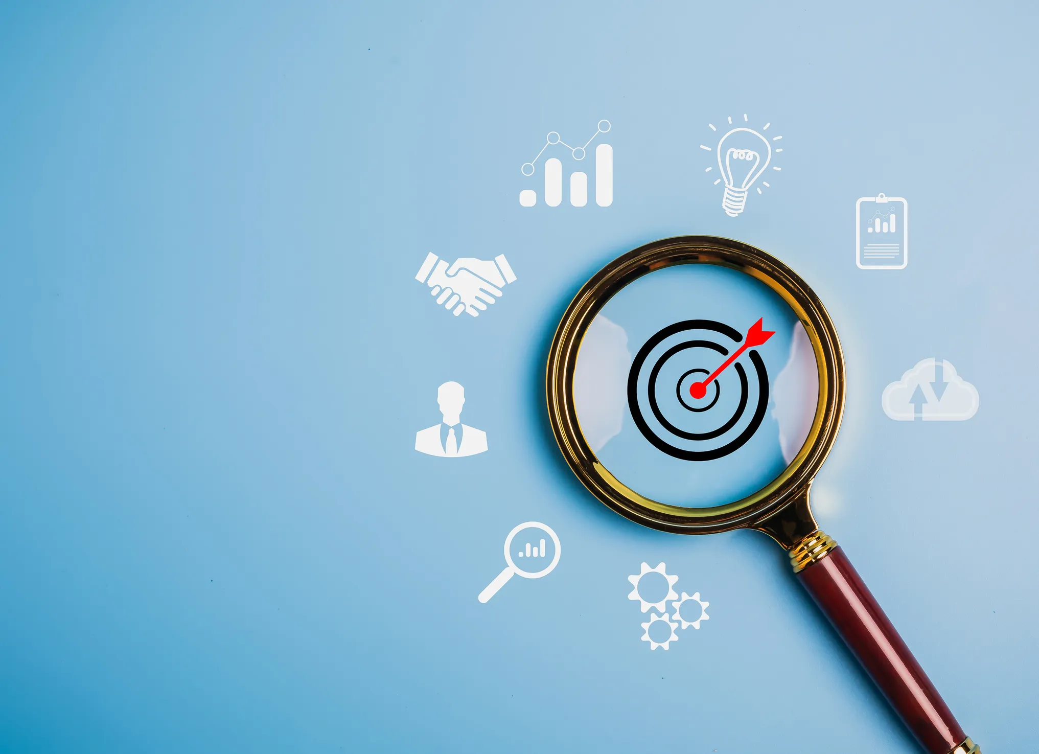Magnifying glass focusing on a target icon surrounded by corporate symbols.